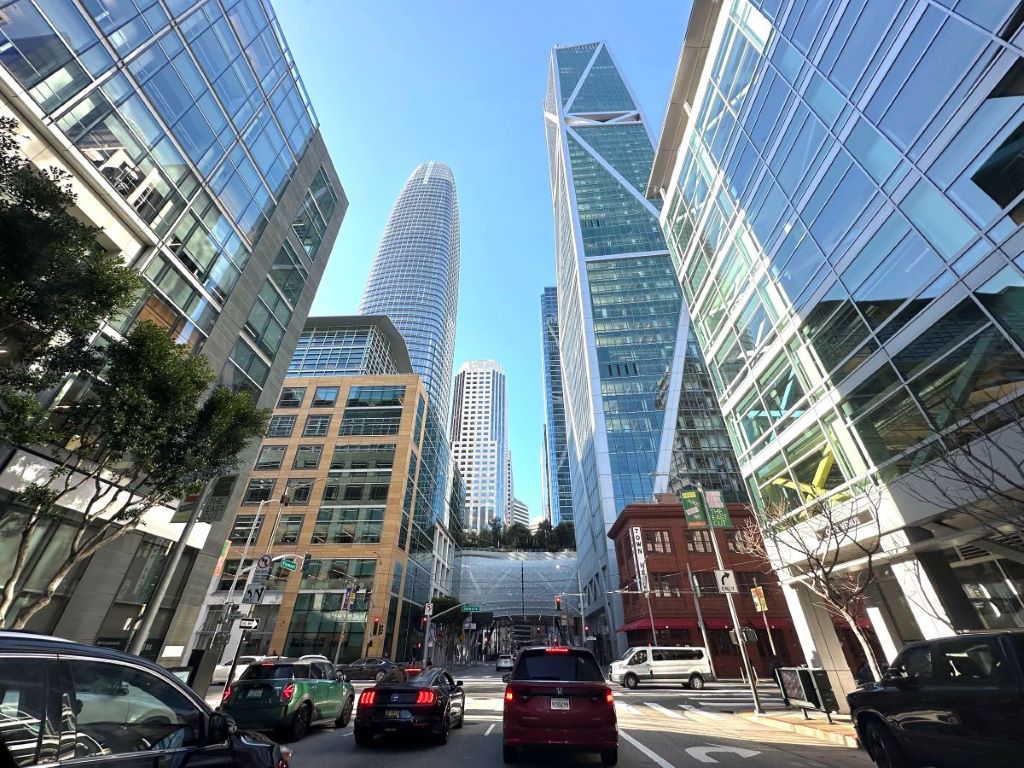 a busy city street filled with cars and skyscrapers against a blue sky